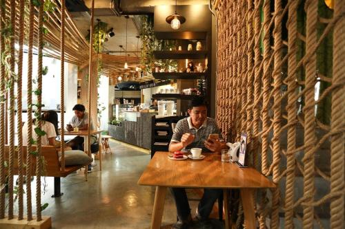 un homme assis à une table dans un restaurant dans l'établissement JK LIVING Hotel And Service Apartment, à Chachoengsao