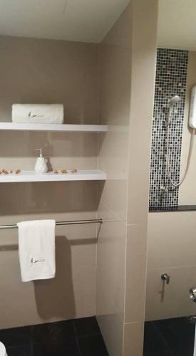 a bathroom with a shower and white towels on shelves at JK LIVING Hotel And Service Apartment in Chachoengsao