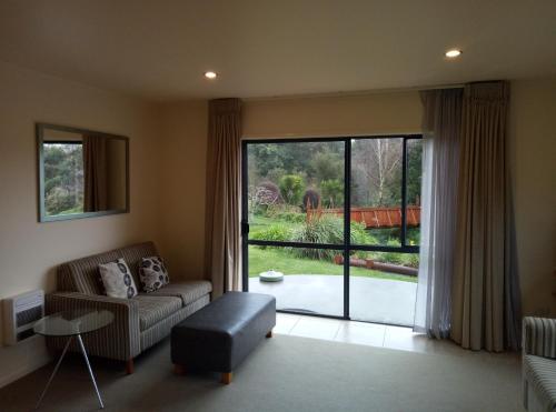 a living room with a couch and a large window at Patons Rock Beach Villas in Takaka