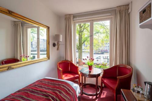 una camera d'albergo con tavolo, sedie e finestra di Amsterdam House Hotel ad Amsterdam