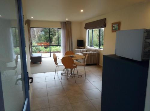 a kitchen with a table and chairs and a living room at Patons Rock Beach Villas in Takaka
