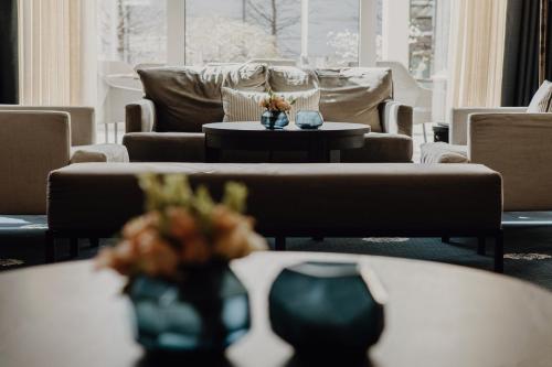 a living room with couches and tables with flowers at Hotel Vier Jahreszeiten Starnberg in Starnberg