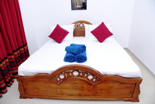a bedroom with a wooden bed with blue sheets and pillows at White Villa Airport Transit Hotel in Katunayake