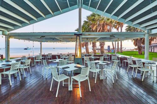 ein Restaurant mit Tischen und Stühlen und der Strand in der Unterkunft RAC Monkey Mia Dolphin Resort in Monkey Mia