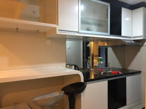 a kitchen with white cabinets and a black counter top at Nagoya Mansion Apartment Batam in Nagoya