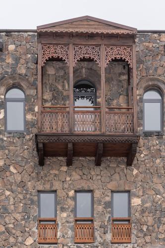 a wooden balcony on a stone building with three windows at Apricot Hotel Yerevan in Yerevan