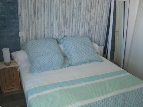uma cama com almofadas azuis e brancas em Au cœur de Port Fréjus - T2 30 m² - Tout à pied em Fréjus