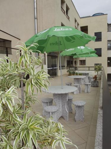 a table and chairs with a green umbrella at Hotel Mares do Sul in Tramandaí