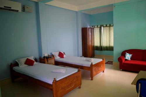 a room with two beds and a red couch at Sewak Lodge in Silchar