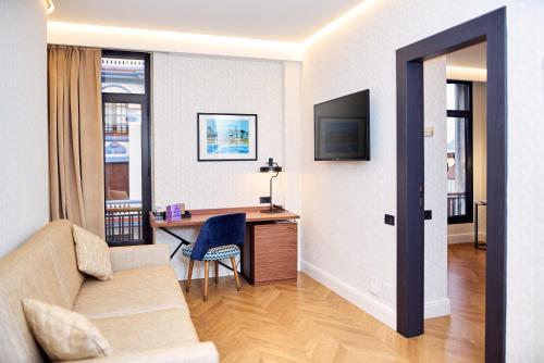 a living room with a couch and a desk at Occidental León Alfonso V in León