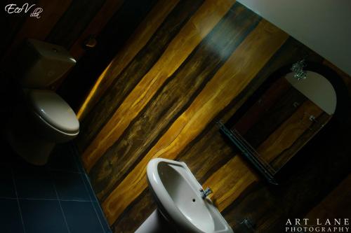 a bathroom with a toilet and a sink and a mirror at Eco Villa - Sinharaja in Deniyaya