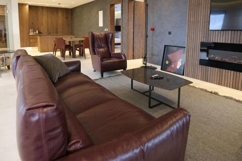 a living room with a brown leather couch and a fireplace at Astoria Luxury & SPA in Gjilan