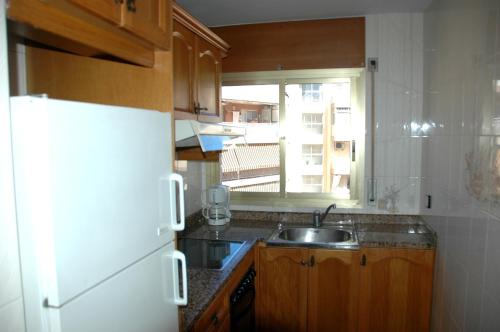 a kitchen with a sink and a white refrigerator at Apartamentos Indasol in Salou