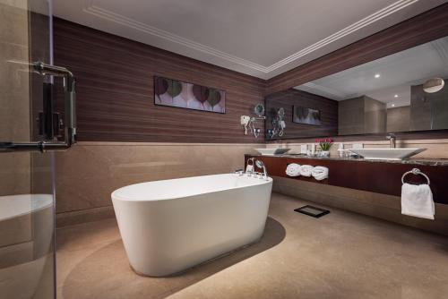 a bathroom with a large tub and a sink at Rua Al Hijrah Hotel in Medina