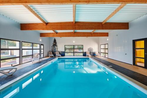 een groot zwembad met blauw water in een huis bij Village by logis in Le Gâvre