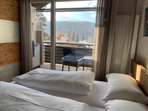 a bedroom with two beds and a balcony with a piano at Studio Top im des Alpes in Flims
