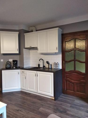 a kitchen with white cabinets and a wooden door at Apartamenty Villa Akant in Piechowice