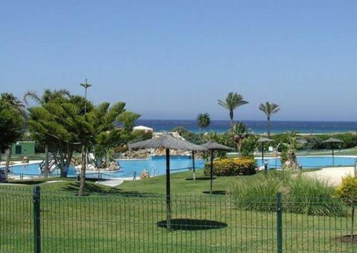 a resort with a pool with umbrellas and the ocean at ATICO DUPLEX APARTAMENTO ATLANTERRA PLAYA, ZAHARA DE LOS ATUNES in Zahara de los Atunes
