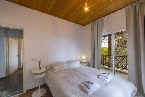 a white bedroom with a large bed and a window at Platres Forest View Cottage in Platres