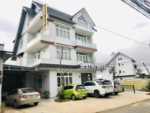 un bâtiment blanc avec des voitures garées devant lui dans l'établissement Spring Hotel, à Đà Lạt