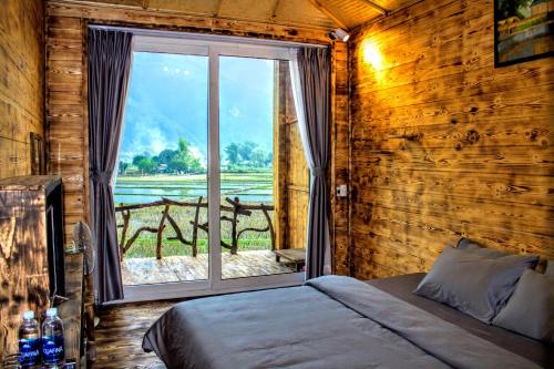 ein Schlafzimmer mit einem Bett und einem großen Fenster in der Unterkunft Mai Chau Countryside Homestay in Mai Châu