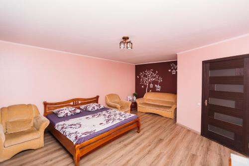 een slaapkamer met een bed en 2 stoelen bij VIP Apartments Faraon on Kharkovskaya 5 floor in Sumy