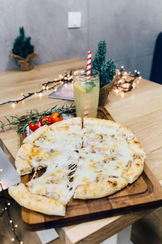 a cheese pizza on a wooden table with a drink at Smile apARTment in Novi Sad