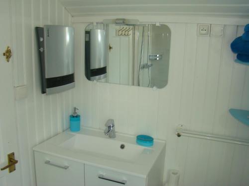 Baño blanco con lavabo y espejo en Kernel Bihan en Pont-lʼAbbé