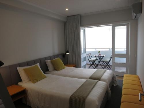 a hotel room with two beds and a balcony at RockInn Porto in Vila Nova de Gaia