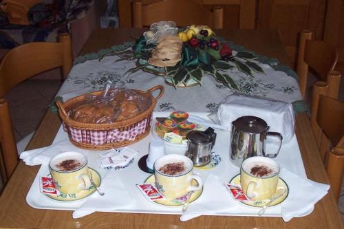 a table with cups of coffee and a basket of food at B&B Ilys in Cava deʼ Tirreni