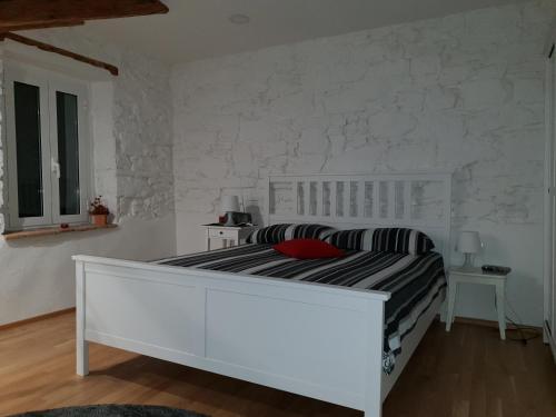 a white bedroom with a bed and a white wall at Stone Wall Apartment Izola in Izola