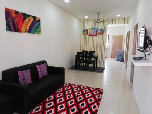 Neesa Homestay Bukit Gambang-Muslim في غامبانغ: غرفة معيشة مع أريكة سوداء وسجادة حمراء