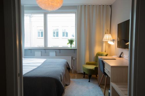 a hotel room with a bed and a desk and a window at Hotell Aston in Karlskrona