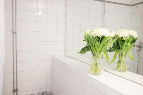 two vases with white flowers sitting on a shelf in a bathroom at Hotell Aston in Karlskrona