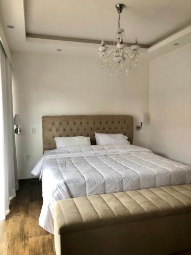 a bedroom with a large white bed with a chandelier at Guest House Recanto da Montanha in Cunha