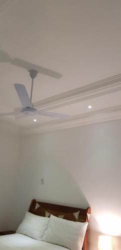 a bedroom with a ceiling fan and a bed at Heather's Retreat in Brufut
