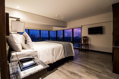 a bedroom with a large bed and large windows at 1898 Hotel Colonia En Las Filipinas in Manila