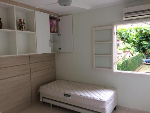 a small room with a bed and a window at Recanto da Enseada - Condomínio Via Marina in Ubatuba