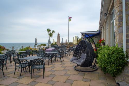 a patio with tables and chairs and the ocean at Berry Head Hotel in Brixham