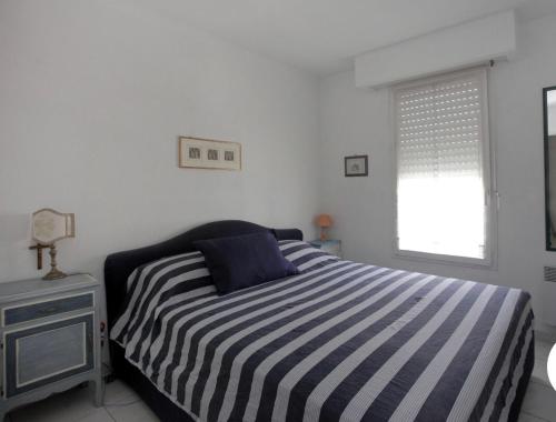 - une chambre avec un lit rayé et une fenêtre dans l'établissement Charme Appartement avec Terrasse, à Cannes