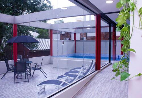 a glass house with a swimming pool on a deck at San Remo Viking Hotel in Pinamar