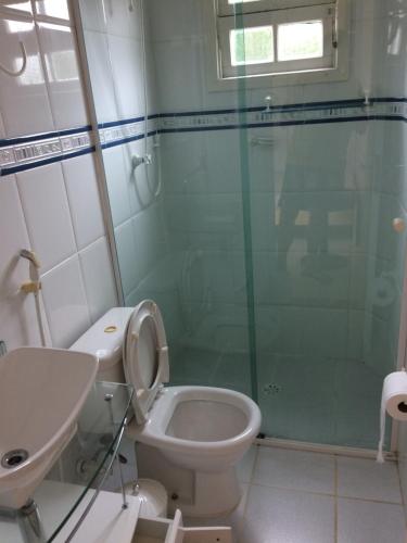 a bathroom with a toilet and a glass shower at Recanto da Enseada - Condomínio Via Marina in Ubatuba