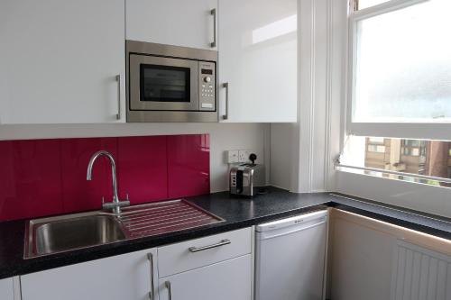 a kitchen with a sink and a microwave at New Mansion House (Lancaster Gate) in London