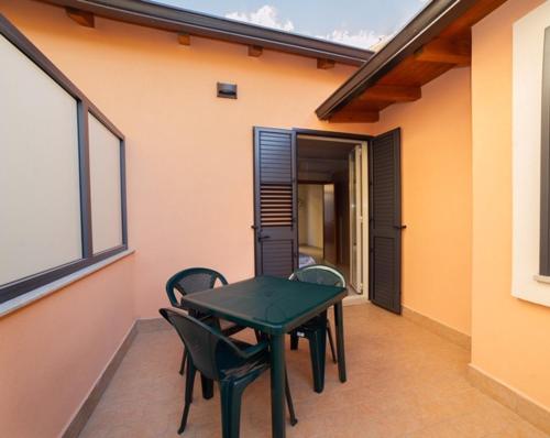 a green table and chairs on the balcony of a house at Casa del Melograno 42 in Roccalumera