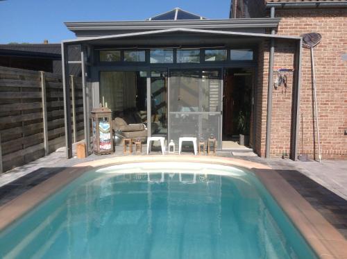 a swimming pool in front of a house at B&B Agnes in Vlissegem