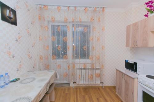 a kitchen with a window with flowers on the wall at Apartment on Sarayshyq in Astana
