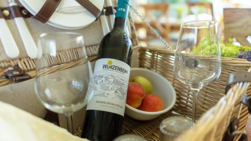 a bottle of wine sitting next to a bowl of fruit at WURZENBERG Hotel Lodges Südsteiermark in Gamlitz