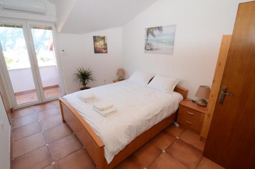 una camera da letto con un letto con lenzuola bianche e una finestra di Maritimo Apartments a Kotor (Cattaro)