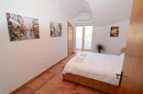 a bedroom with a bed and some pictures on the wall at Maritimo Apartments in Kotor