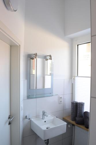 een witte badkamer met een wastafel en een spiegel bij Diepholzer–Boardinghouse in Diepholz